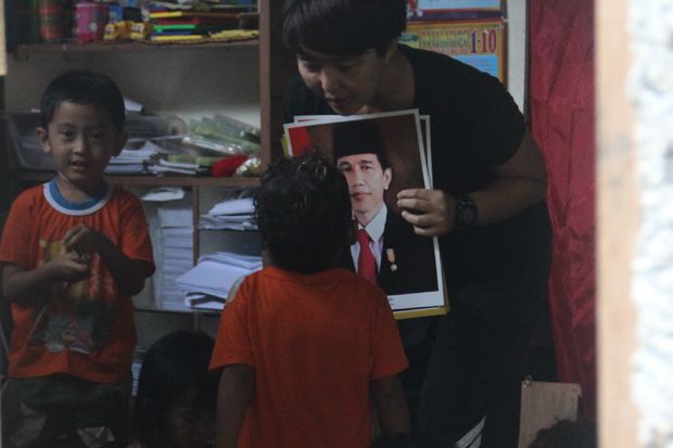 Niramita Ayu bertanya tentang sosok yang ada dalam poster yang dia pegang kepada anak-anak didiknya di taman baca yang dia dirikan. Foto/KORAN SINDO MANADO/Valentino Warouw
